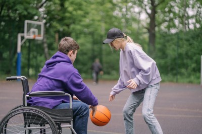 Chlapec na vozíku a dievča hrajú basketbal