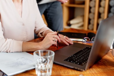Laptop s pohárom na stole a ženské ruky