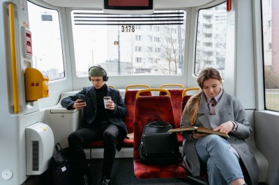 Mladí cestujú v električke a pozerajú do mobilu