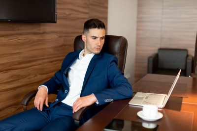 Mladý muž v obleku sedí za písacím stolom