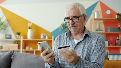 Senior v ruke s kalkulačkou a platobnou kartou