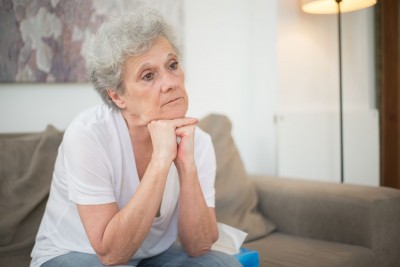 Seniorka sedí a podpiera si halvu